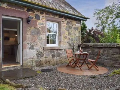 a table and chairs outside of a stone cottage at The Old Stables At Westerton in Crieff