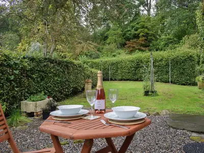 a wooden table with a bottle of wine and glasses at The Old Stables At Westerton in Crieff