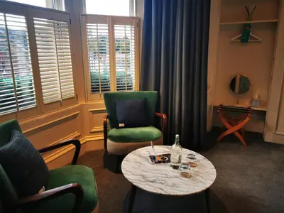 a living room with a table and a green chair and a table and chairs at The Balerno Inn in Edinburgh