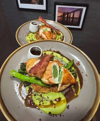 two plates of food with chicken and vegetables on a table at The Balerno Inn in Edinburgh