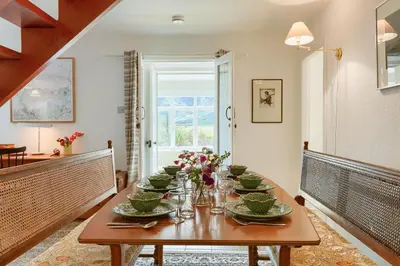 a dining room with a wooden table with flowers on it at Enchanting,rustic, Dundurn Mill with stunning views and private river in Comrie