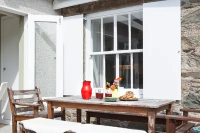 a wooden table on a patio with a window at Enchanting,rustic, Dundurn Mill with stunning views and private river in Comrie