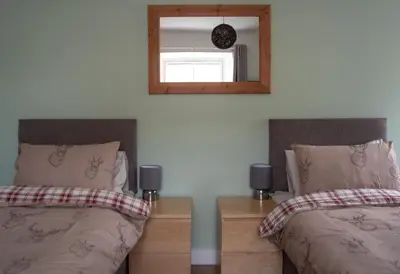 a bedroom with two beds and a mirror at Altquhur Byre in Drymen