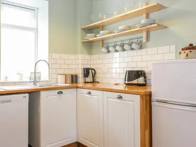 a kitchen with white cabinets and a white refrigerator at Daisy Cottage in Moffat