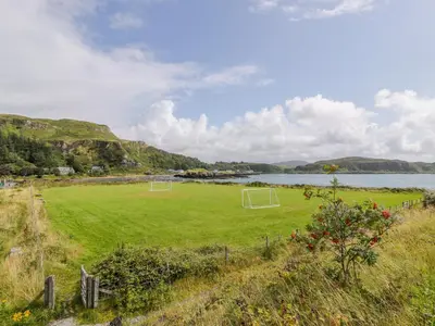 a field with two soccer goals on it next to a body of water at Grebe Cottage in Oban