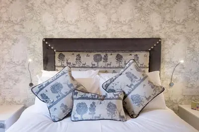 a bed with blue and white pillows on it at Deerstalker Lodge cozy lodge with wood burner in Crianlarich
