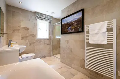 a bathroom with a sink toilet and a television on the wall at Deerstalker Lodge cozy lodge with wood burner in Crianlarich
