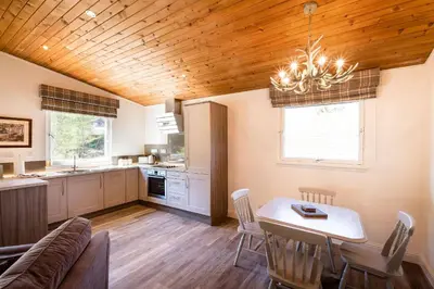 a kitchen and dining room with a table and chairs at Deerstalker Lodge cozy lodge with wood burner in Crianlarich