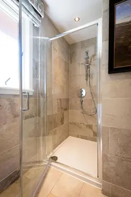 a bathroom with a shower with a glass door at Deerstalker Lodge cozy lodge with wood burner in Crianlarich