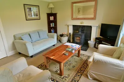 a living room with couches and a table and a fireplace at Gardeners Cottage in Chesthill