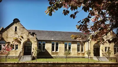 an old brick building with a fence in front of it at The Old Schoolhouse, Kinross in Kinross
