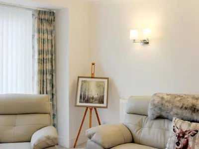 a living room with a couch and a chair at Rhunahaorine Cottage in Gortinanane