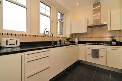 a kitchen with white cabinets and black counter tops at Signature - Greenlees Clubhouse 3 Bed in Cambuslang