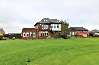 a large brick house with a green yard at Signature - Greenlees Clubhouse 3 Bed in Cambuslang