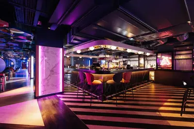 a nightclub with a bar with purple lighting and stools at YOTEL Glasgow in Glasgow