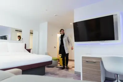a man standing in a hotel room with a tv at YOTEL Glasgow in Glasgow