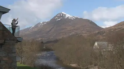 a man standing on the balcony of a house with a mountain at Highland Getaway in Kinlochleven