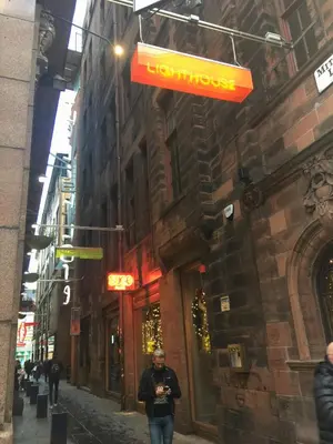 a man walking down a street with a sign on a building at Glasgow Emo in Glasgow