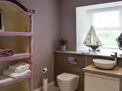 a bathroom with a toilet and a sailboat on a shelf at Torcross Barn in Tarbolton