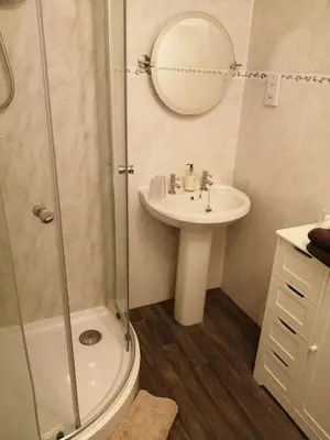 a bathroom with a shower and a sink and a mirror at Don Muir Guesthouse in Oban