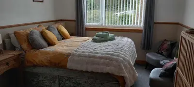 a bedroom with a bed with a blanket and a window at Don Muir Guesthouse in Oban
