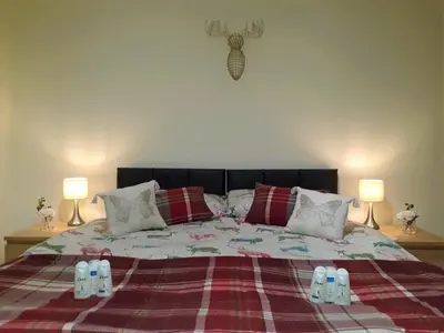 a bedroom with a bed with a blanket and two lamps at Airdrie Apartments in Airdrie