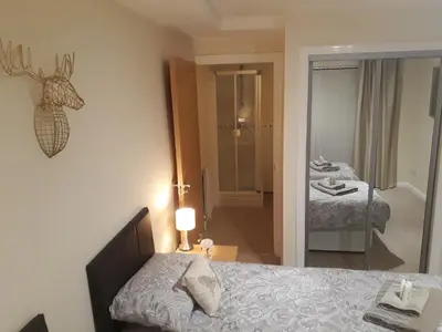 a bedroom with a bed and a bathroom with a mirror at Airdrie Apartments in Airdrie