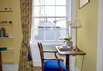 a room with a table and a window with a chair at Thistle Street Apartment at Heart of the City Centre in Edinburgh