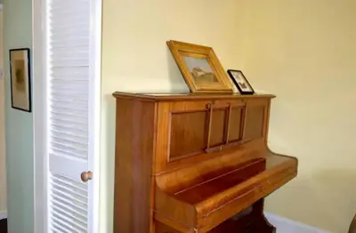 a wooden piano with a picture on top of it at Thistle Street Apartment at Heart of the City Centre in Edinburgh