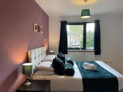 a bedroom with a bed with pillows and a window at Cozy Nights - Cambuslang 1/64 in Glasgow