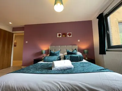 a bedroom with a large bed with blue pillows at Cozy Nights - Cambuslang 1/64 in Glasgow