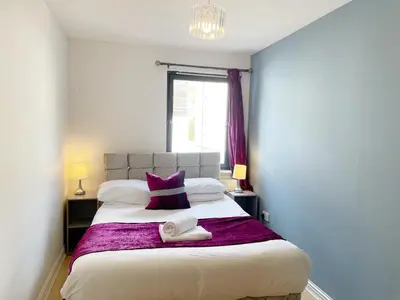 a bedroom with a large bed with a purple blanket at Cozy Nights - Cambuslang 1/64 in Glasgow