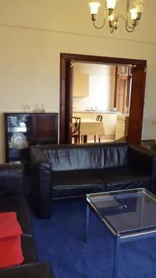 a living room with a black leather couch and a table at Kinneil Self Catering in Lamlash