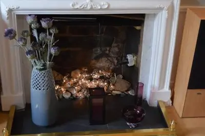a fireplace with a vase of flowers and a candle at castle Apartment 1 in Edinburgh