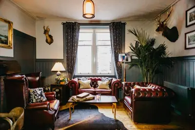 a living room with leather furniture and a window at Coorie Inn Restaurant and Rooms in Crieff