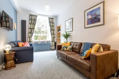 a living room with a brown couch and a chair at Grassmarket Jewel in Edinburgh