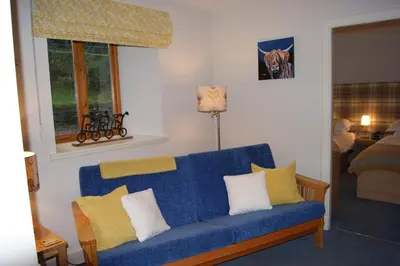 a living room with a blue couch with yellow pillows at Shegarton Farm Cottages in Luss