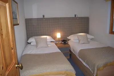 a bedroom with two beds and a lamp on a table at Shegarton Farm Cottages in Luss