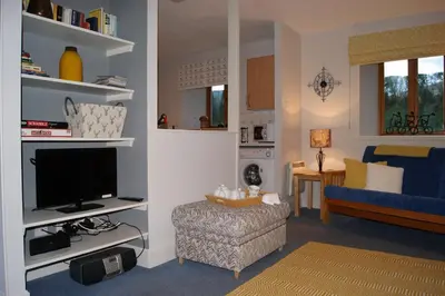 a living room with a tv and a blue couch at Shegarton Farm Cottages in Luss