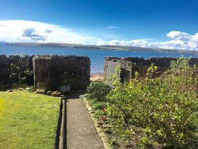 a garden with a fence and a view of the ocean at Beach House No1 With Amazing Sea Views And Direct Beach Access in Fairlie