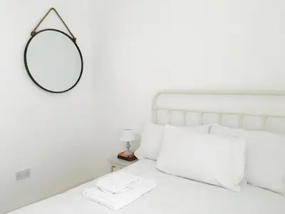 a bedroom with a white bed with a mirror on the wall at Beach House No1 With Amazing Sea Views And Direct Beach Access in Fairlie