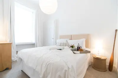 a white bedroom with a white bed and a window at Beach House No1 With Amazing Sea Views And Direct Beach Access in Fairlie