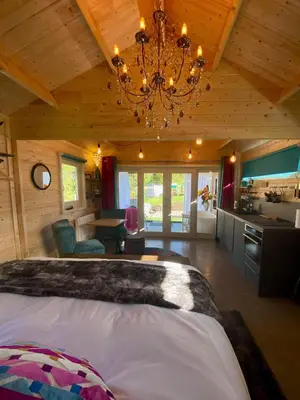 a large bedroom with a chandelier in a cabin at Dunroamin Lodges in Drymen