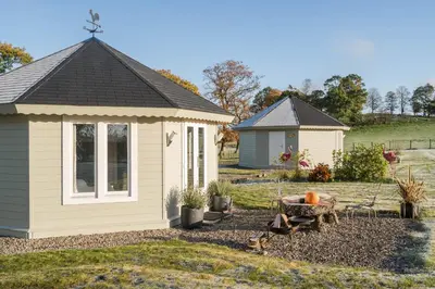 a small shed in a yard with a bench at Dunroamin Lodges in Drymen
