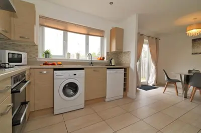 a kitchen with a washer and dryer in it at Signature - Wilkie House in Holytown