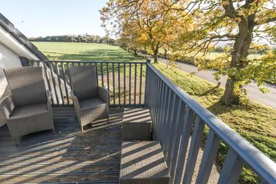 two chairs on a porch with a view of a field at Dunroamin Apartment in Drymen