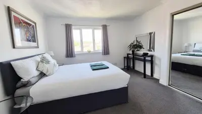 a bedroom with a large bed and a mirror at Levenhowe Holiday Apartment in Balloch