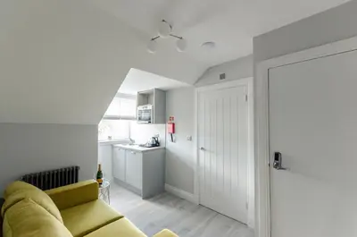 a living room with a yellow couch and a kitchen at Sweeney Motherwell in Motherwell