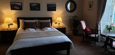 a bedroom with a bed and a table and a chair at CREAG DHUBH COUNTRY HOUSE in Inveraray