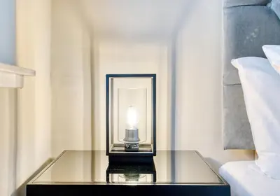 a lamp on a glass table next to a bed at The Gloucester Lane Residence in Edinburgh